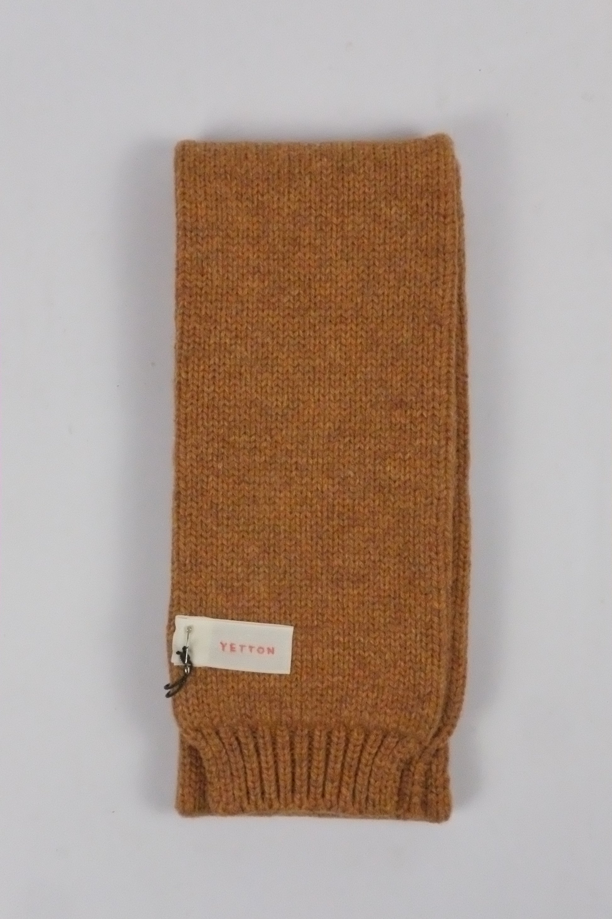 Brown knitted headband with a brand label on a light gray background