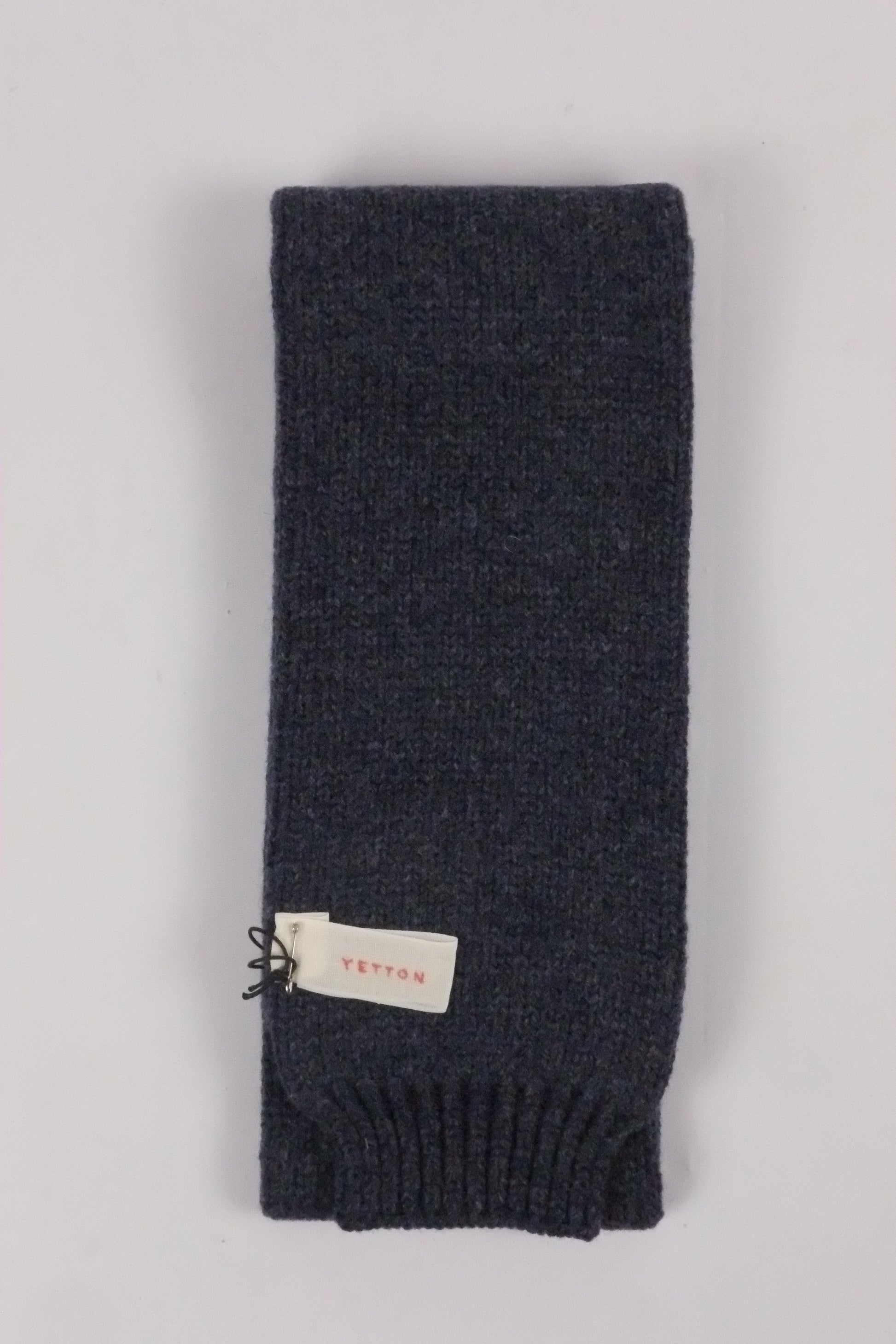Dark gray knit scarf with a brand tag on a light gray background
