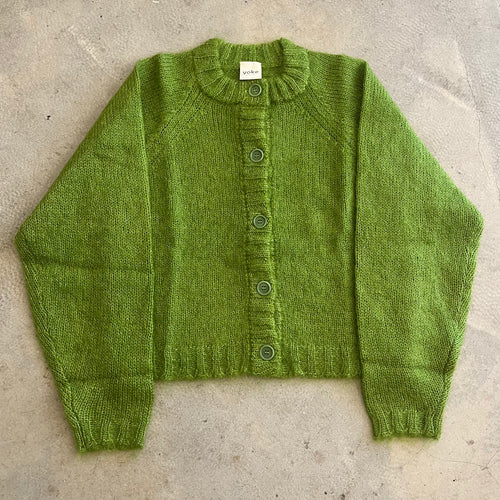 Green knitted cardigan on a concrete surface