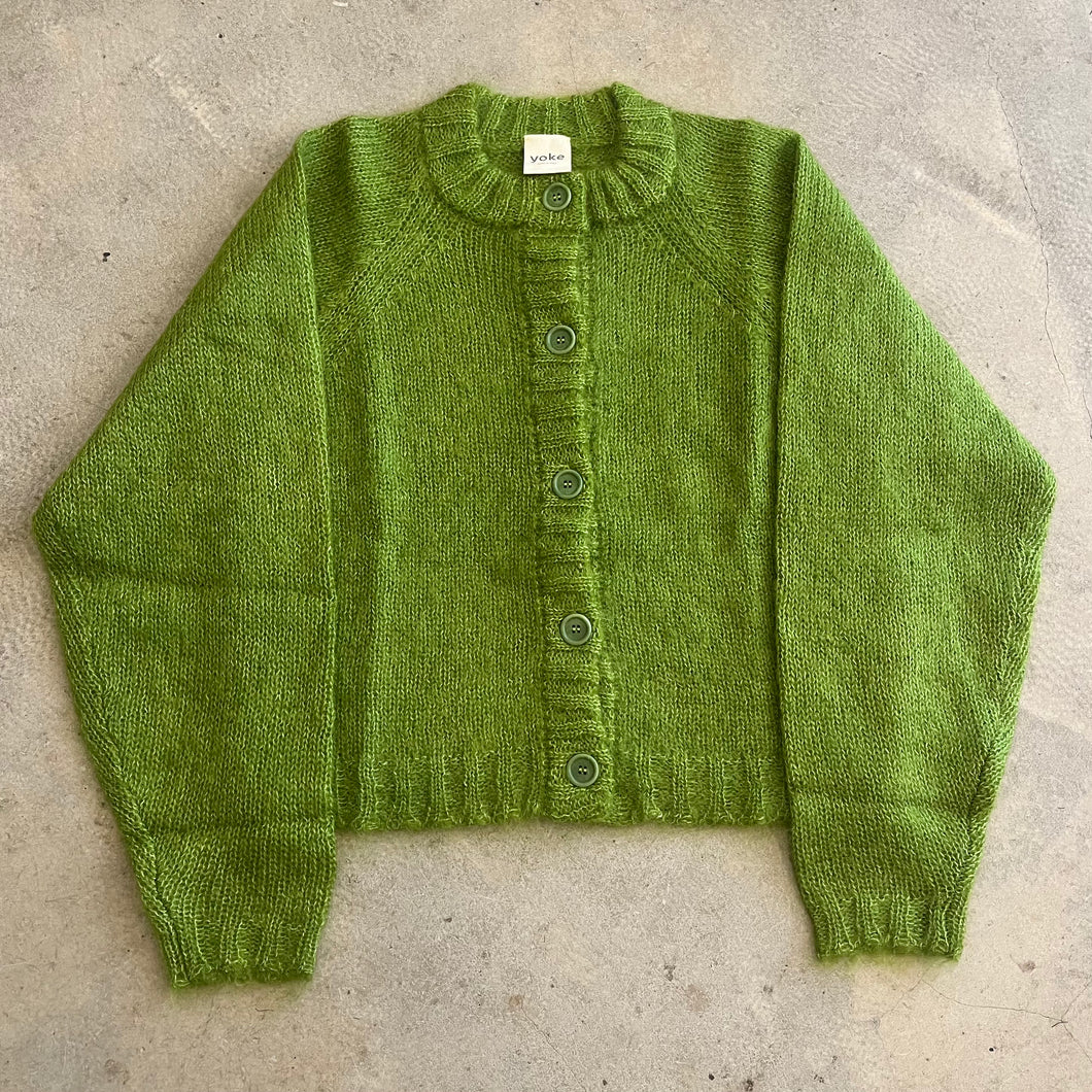 Green knitted cardigan on a concrete surface