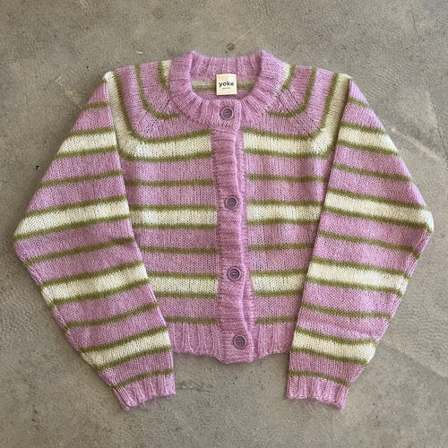 Striped cardigan with pink and green pattern on a concrete surface