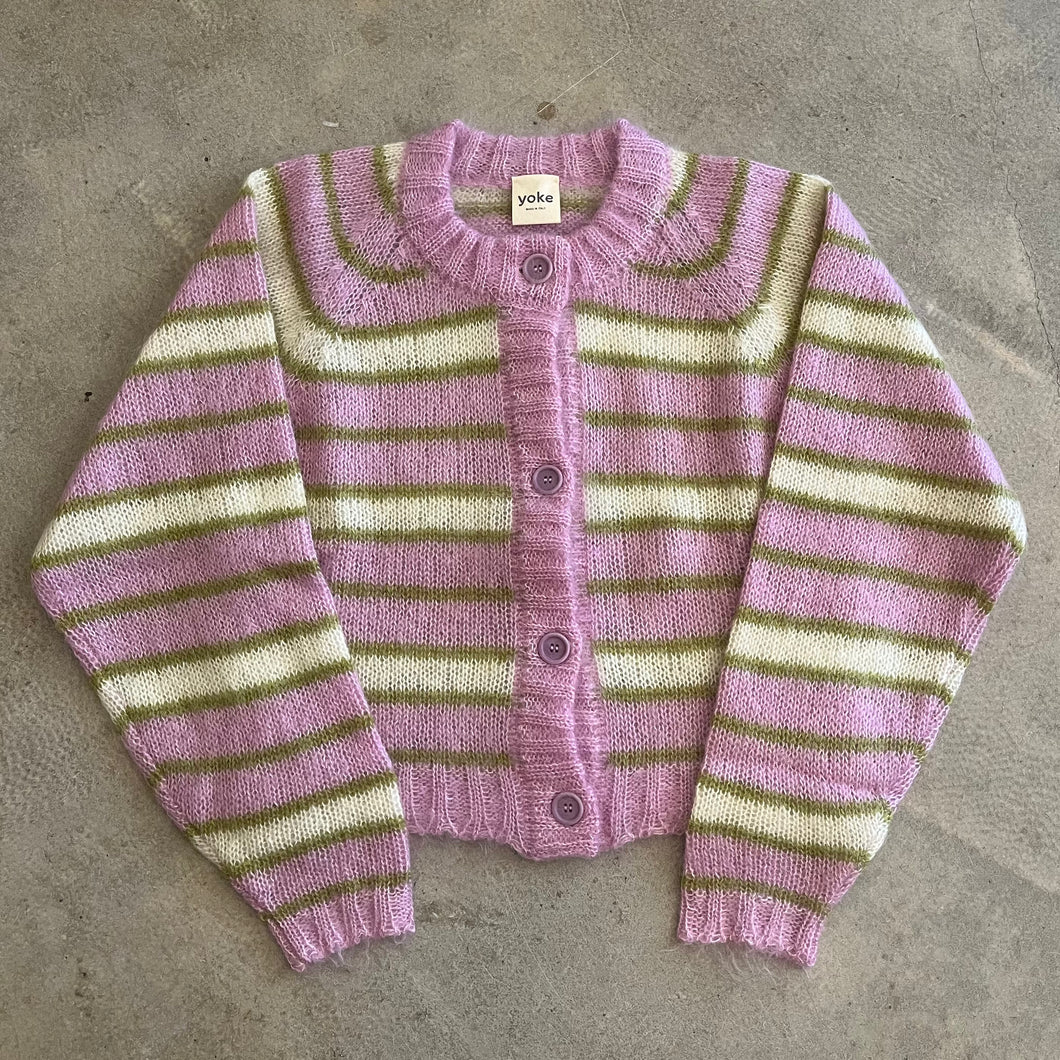 Striped cardigan with pink and green pattern on a concrete surface