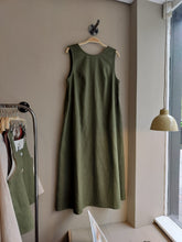 Load image into Gallery viewer, Green linen sleeveless dress hanging on a hanger against a neutral wall.
