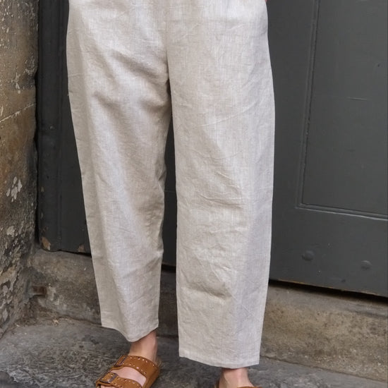 Person wearing light-colored pants and brown sandals on a stone surface.