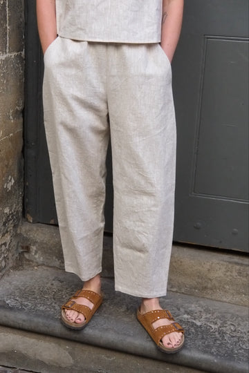 Person wearing light-colored pants and brown sandals on a stone surface.