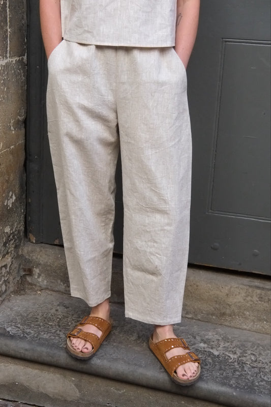 Person wearing light-colored pants and brown sandals on a stone surface.