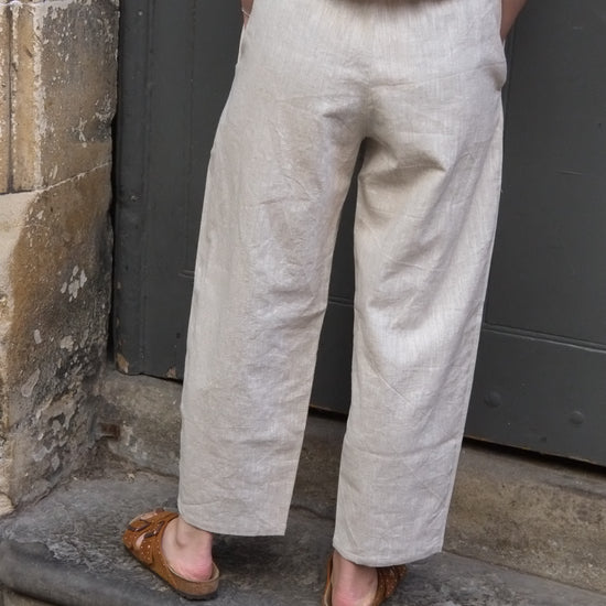 Person wearing beige pants and brown shoes standing on a stone ledge.