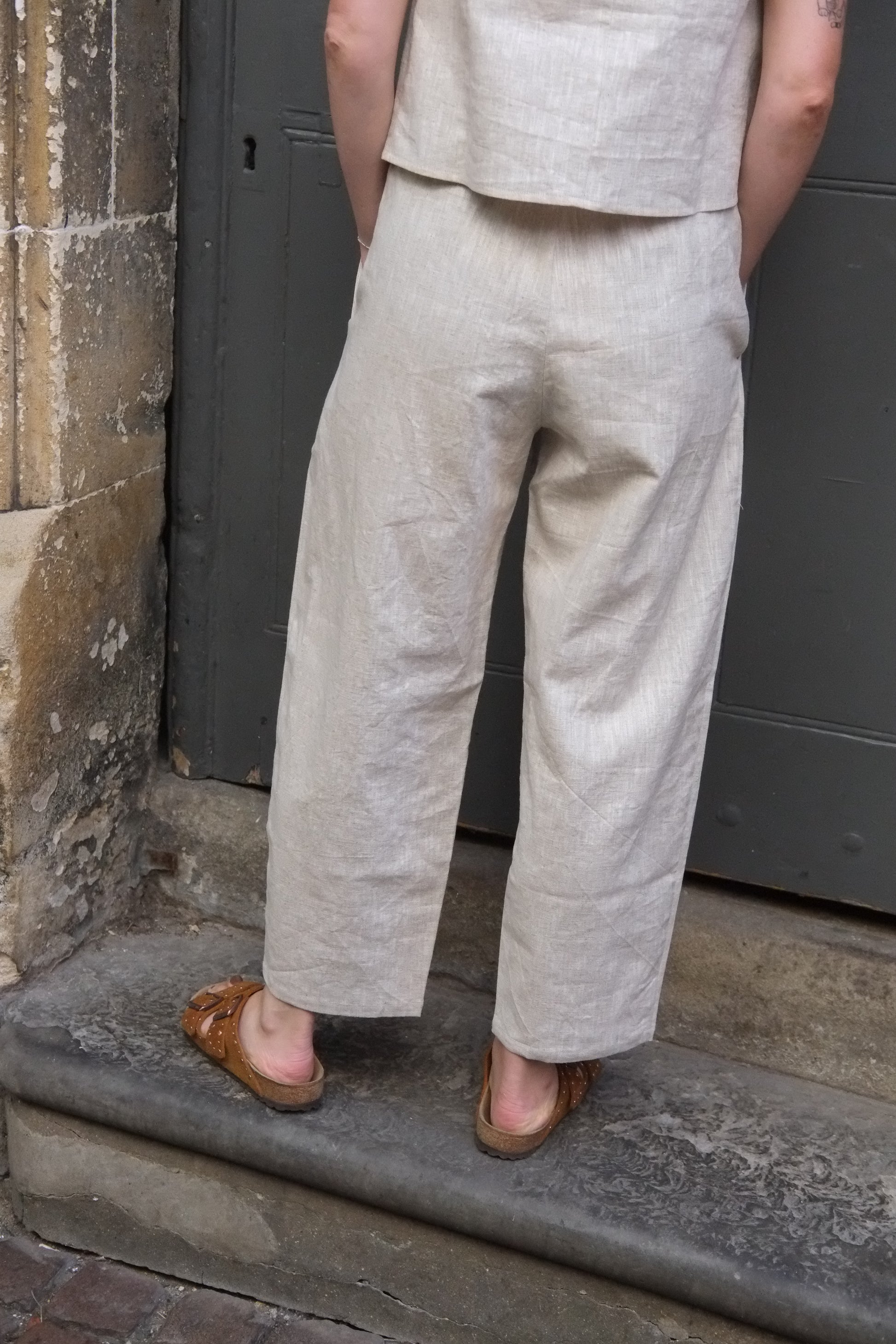 Person wearing beige pants and brown shoes standing on a stone ledge.