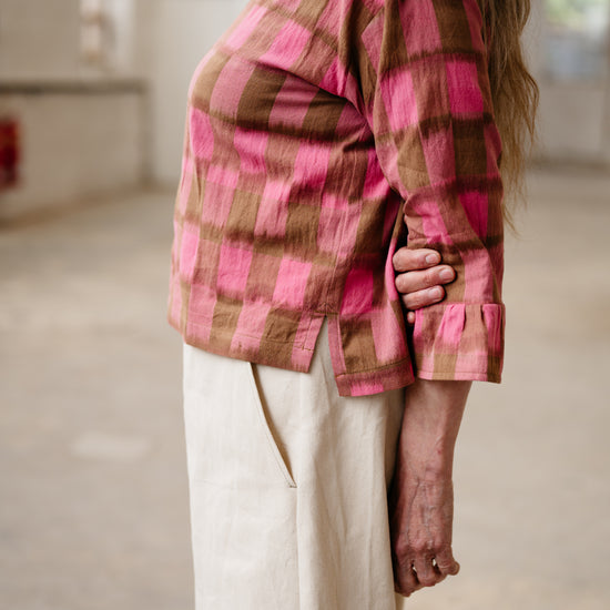 Person wearing a pink and brown plaid shirt in an indoor setting