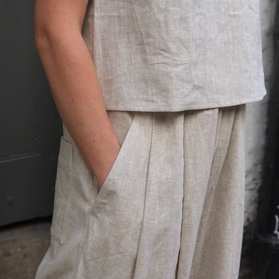 close up of woman wearing light coloured trousers with hand in pocket