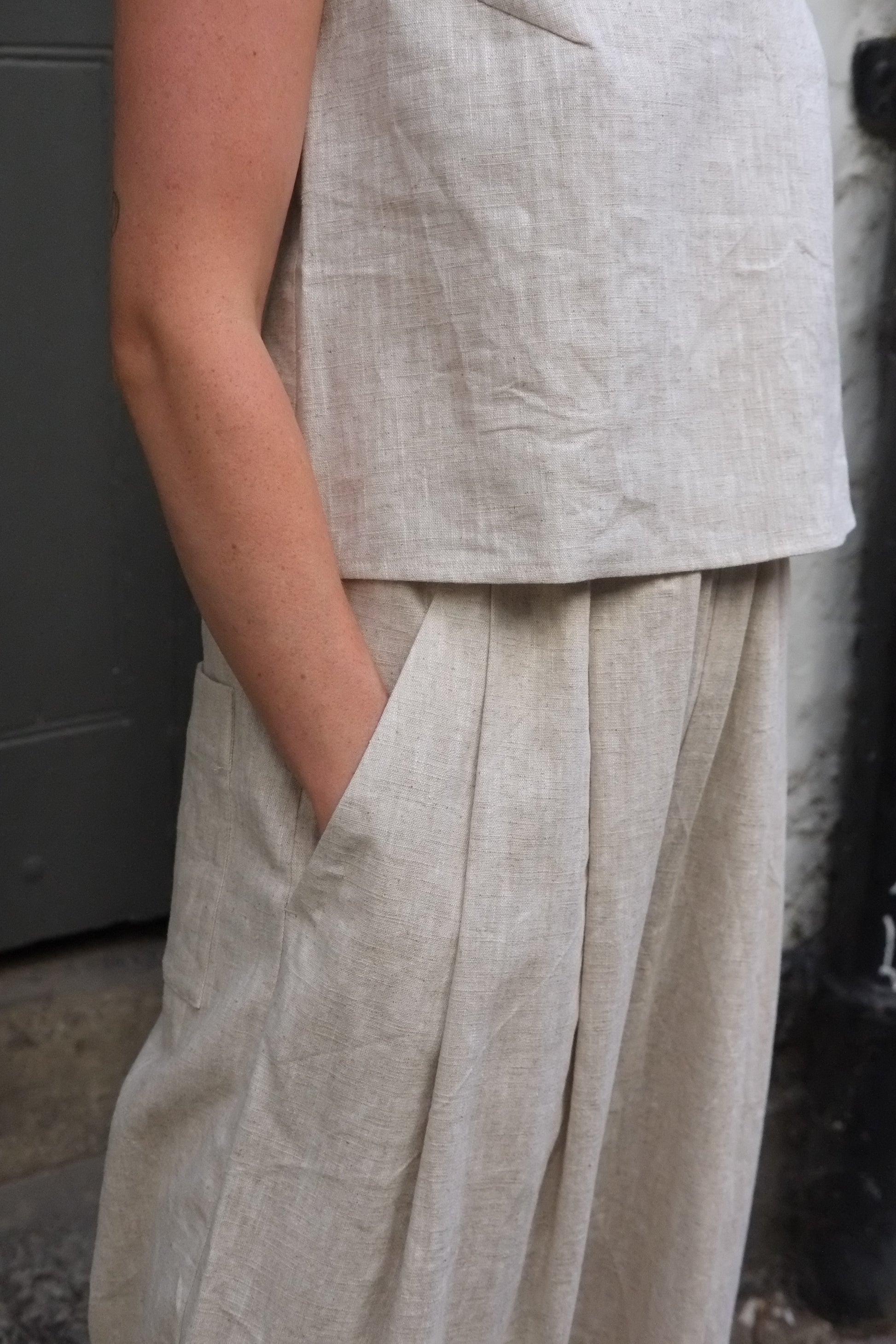 close up of woman wearing light coloured trousers with hand in pocket