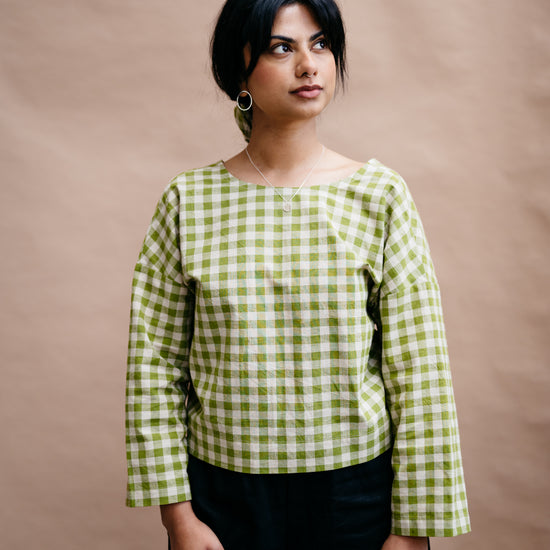 Woman wearing a green and white checkered shirt against a brown background