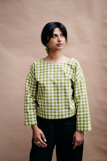 Woman wearing a green and white checkered shirt against a brown background