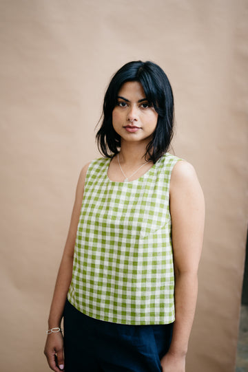 Woman wearing a green checkered top against a beige background