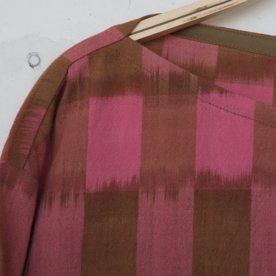 Close-up of a fabric with pink and brown checkered pattern on a white background