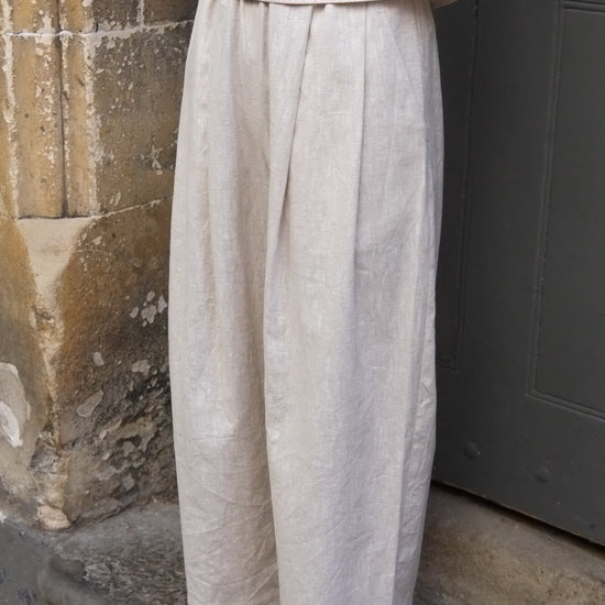 Person wearing light-colored pants and sandals standing on a stone floor.