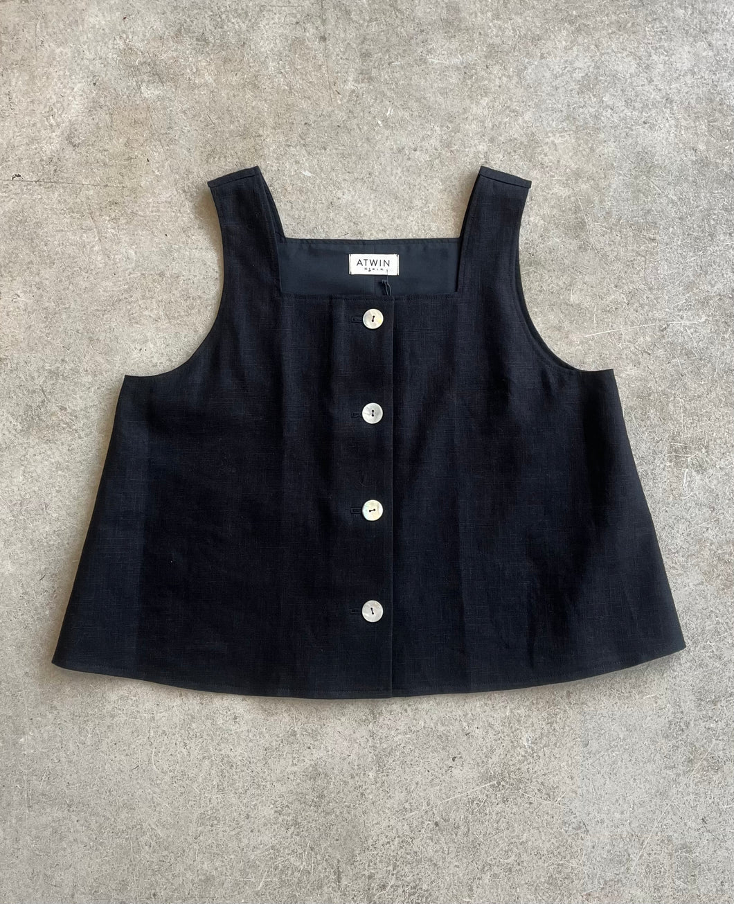 Black sleeveless top with shell button details