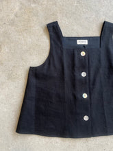 Load image into Gallery viewer, Black sleeveless top with button details on a gray surface, featuring the brand Atwin The Label
