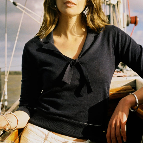 Woman on a sailboat wearing a navy top and beige pants.
