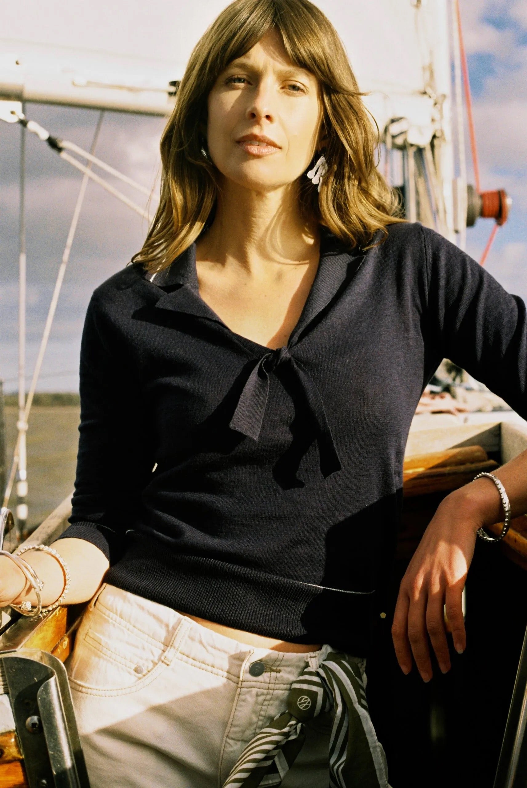 Woman on a sailboat wearing a navy top and beige pants.