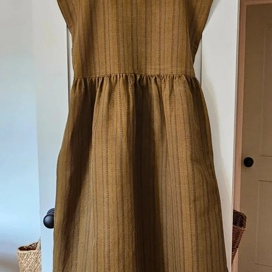 Brown dress on a hanger against a white door.