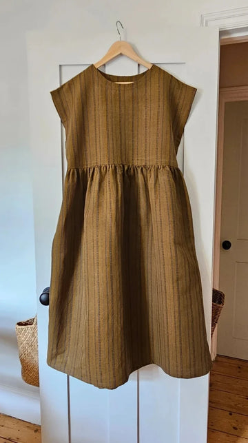 Brown dress on a hanger against a white door.