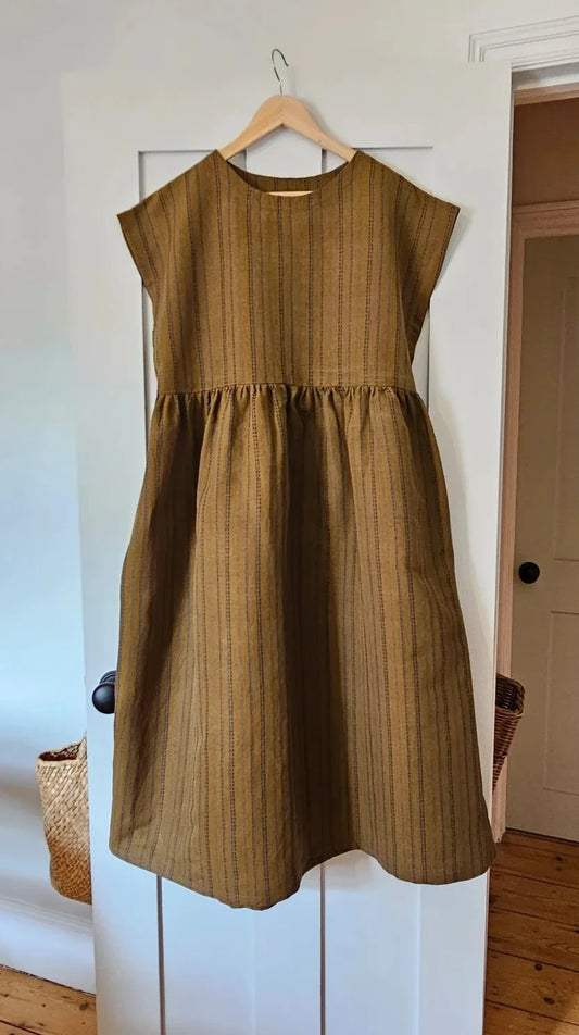 Brown dress on a hanger against a white door.
