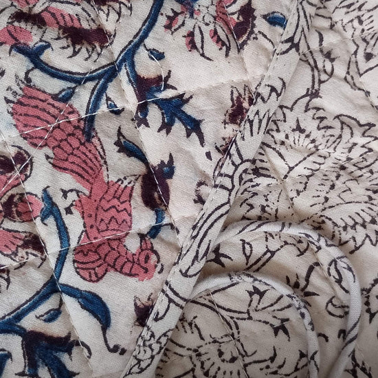 Close-up of patterned fabric with floral and bird designs.