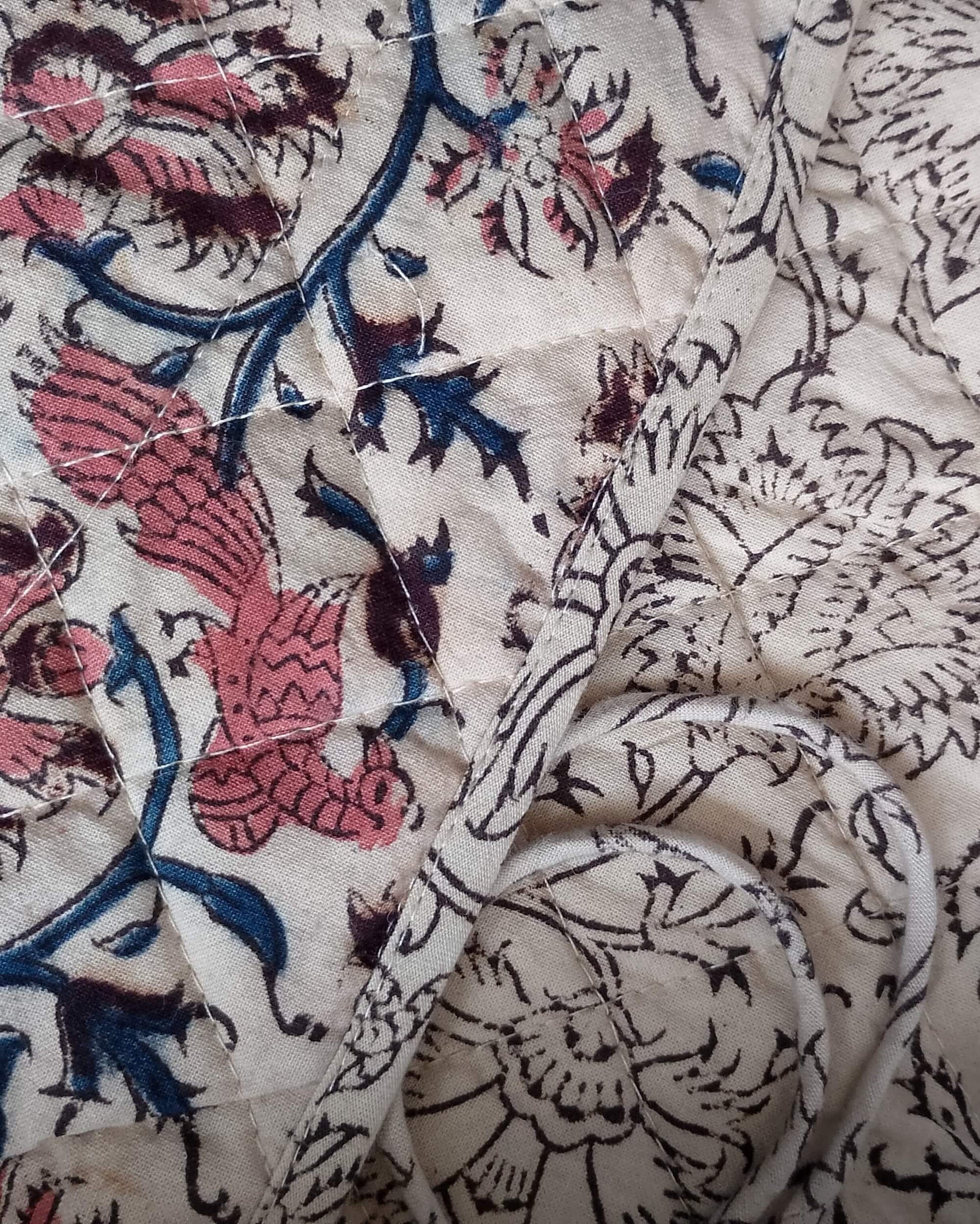 Close-up of patterned fabric with floral and bird designs.