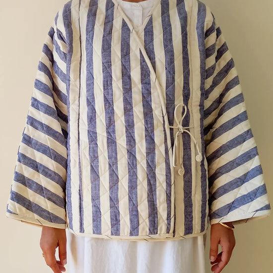 Person wearing a blue and white striped shirt with a plain background