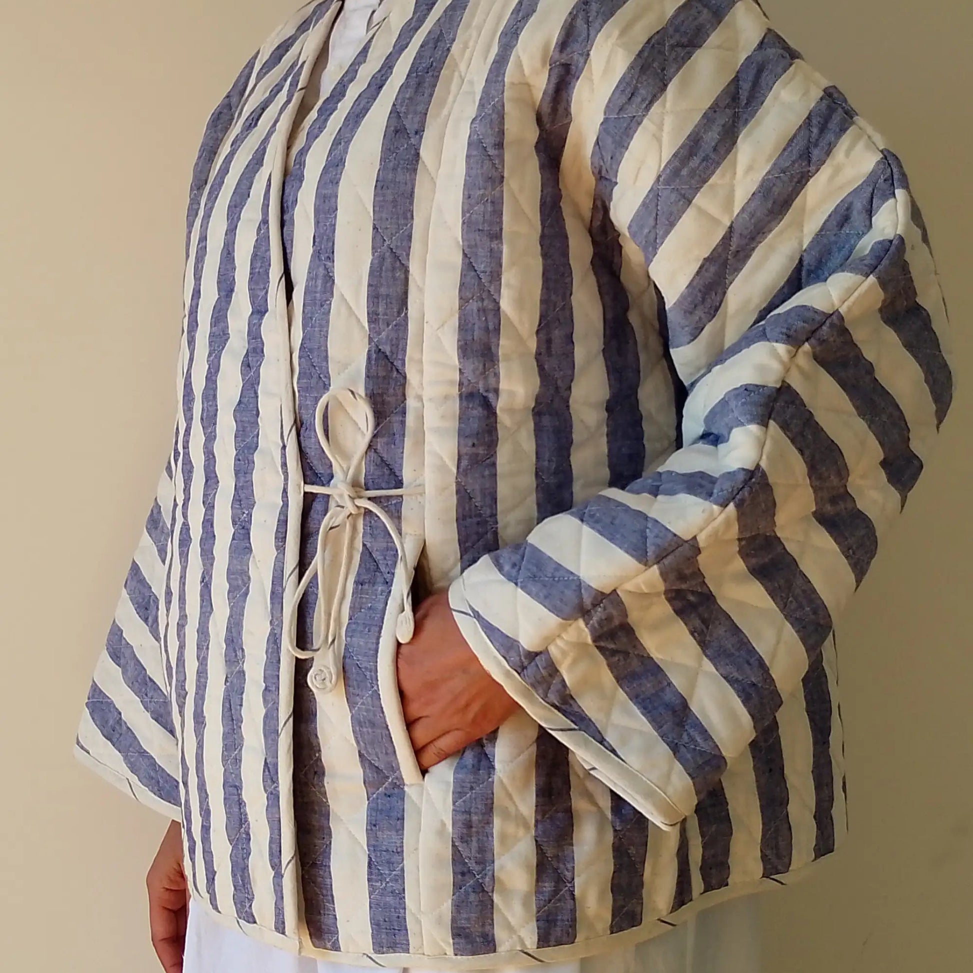 Person wearing a blue and white striped quilted jacket against a plain background