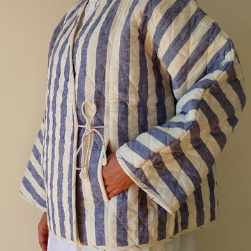Person wearing a blue and white striped quilted jacket against a plain background