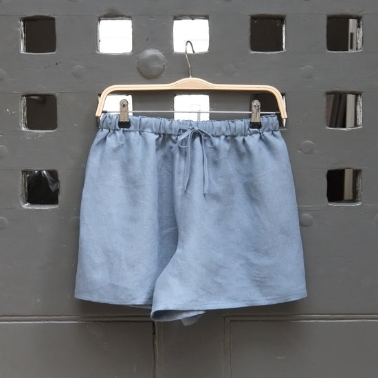 Blue shorts on a metal clip against a perforated metal background