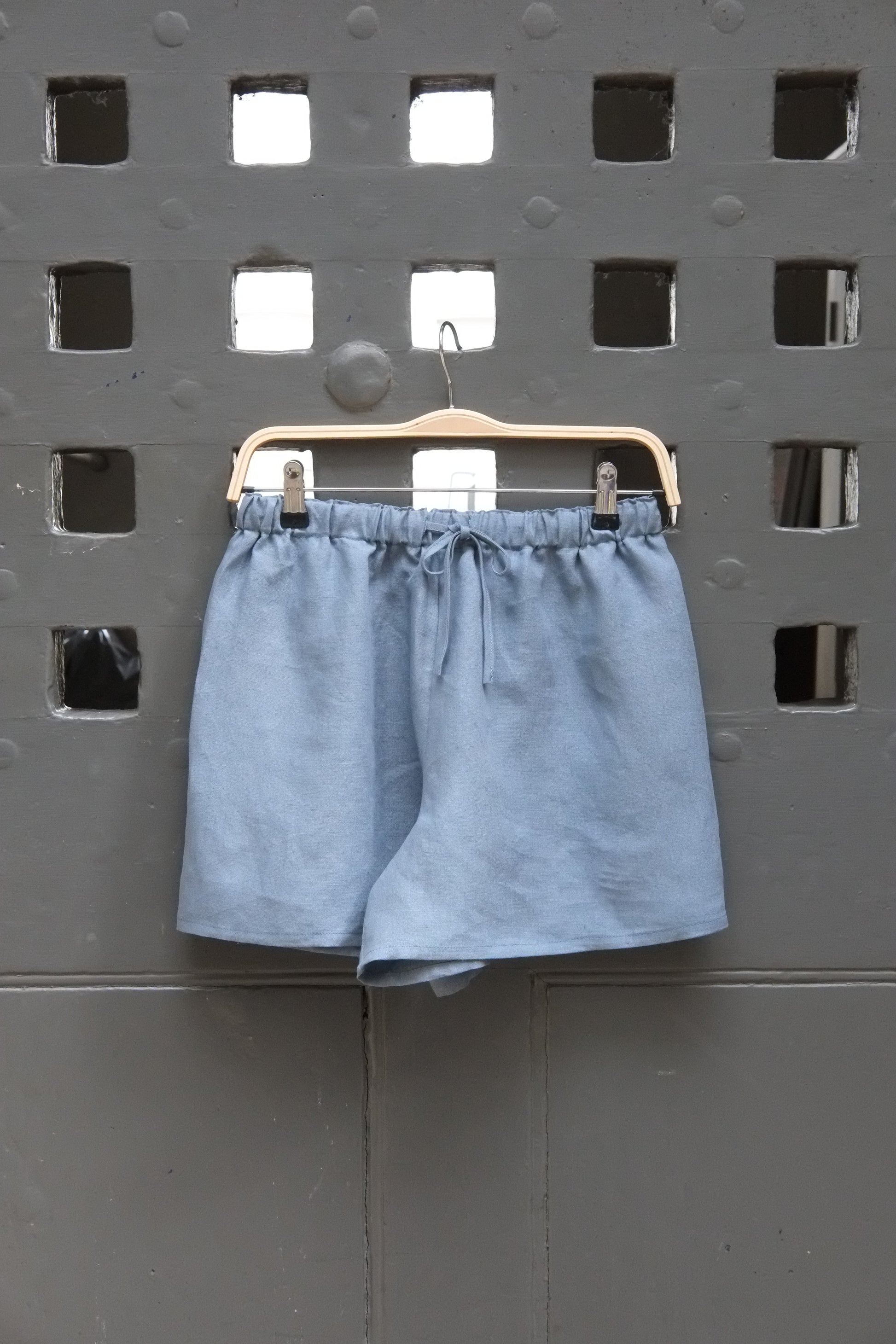 Blue shorts on a metal clip against a perforated metal background