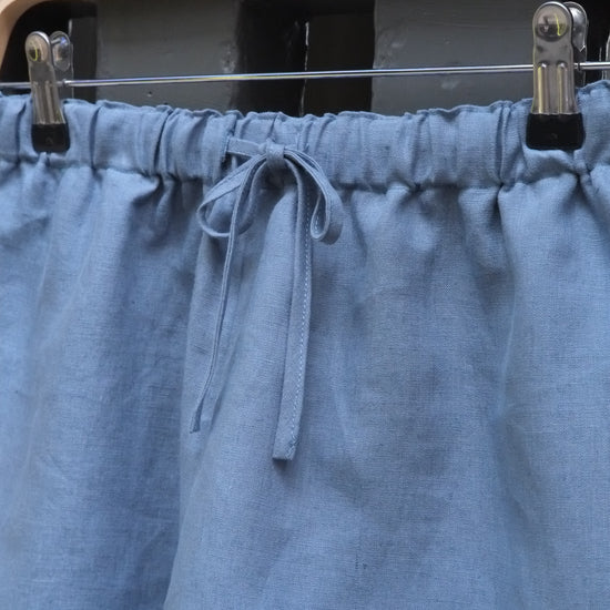 Close-up of a blue fabric with pleats and clips on a dark background
