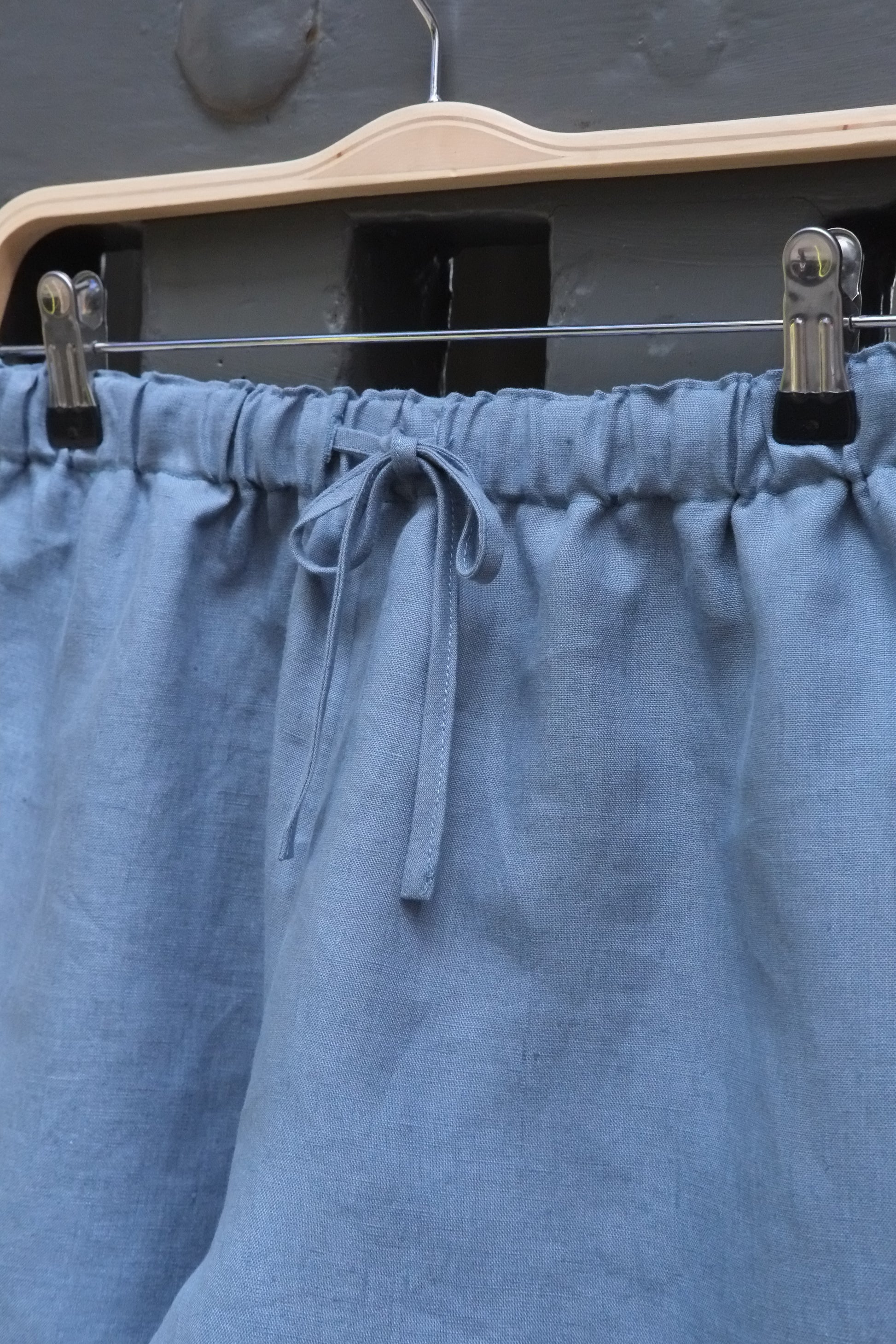 Close-up of a blue fabric with pleats and clips on a dark background