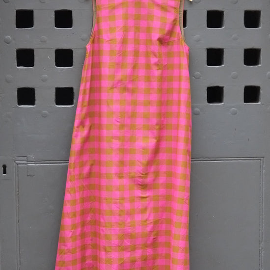 pink and olive green checked sleeveless dress photographed against a grey door