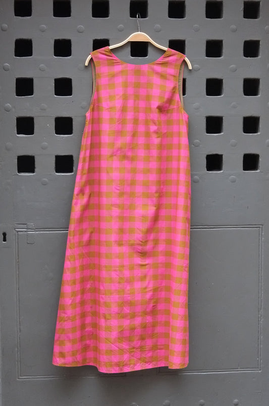 pink and olive green checked sleeveless dress photographed against a grey door
