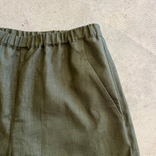 Load image into Gallery viewer, Green linen shorts on a textured beige surface
