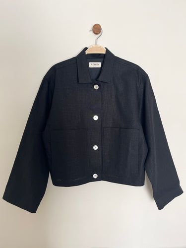Black workwear jacket on a hanger against a white background