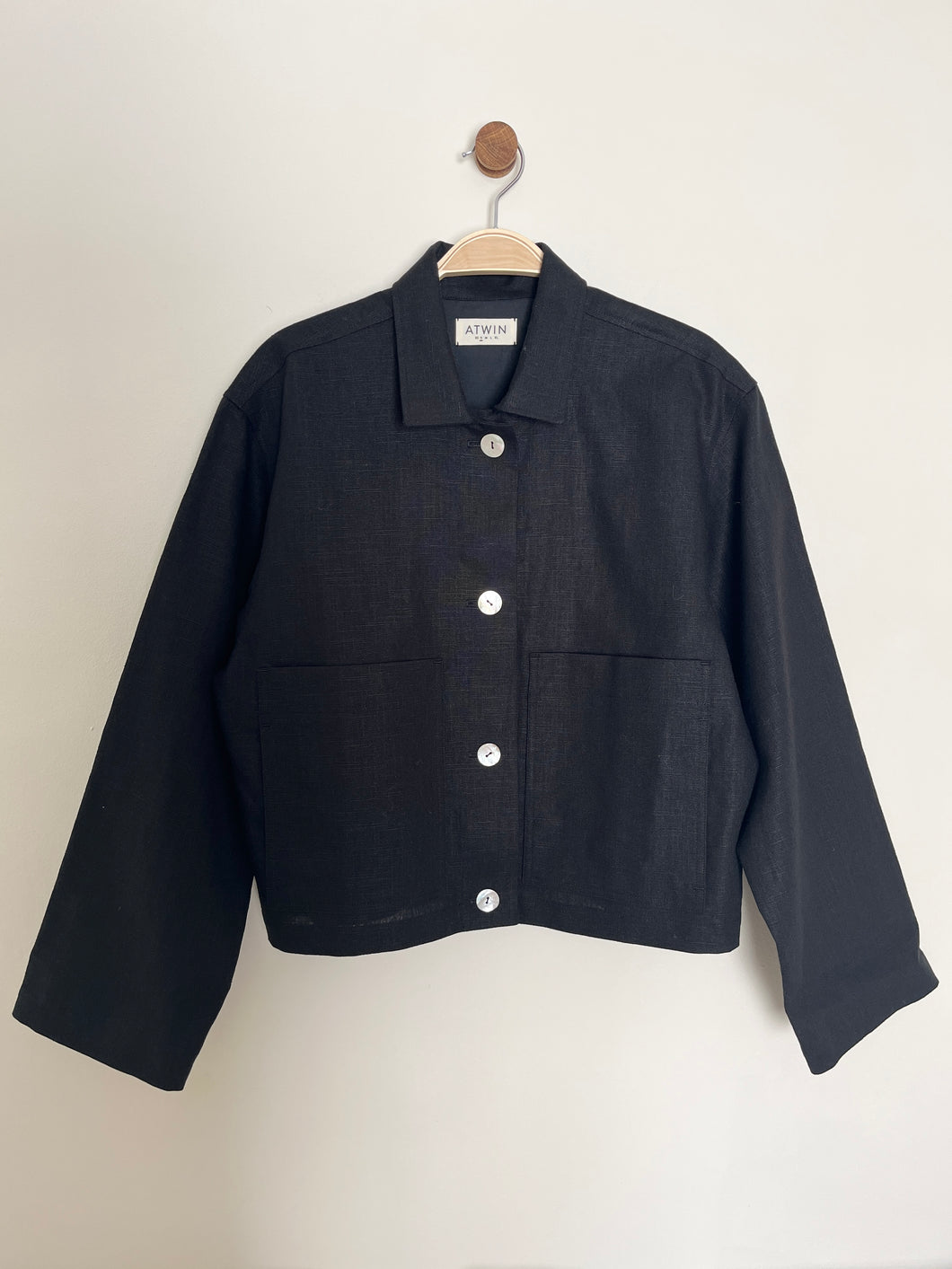 Black workwear jacket on a hanger against a white background