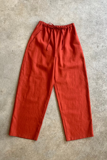 Red linen trousers on a gray concrete floor