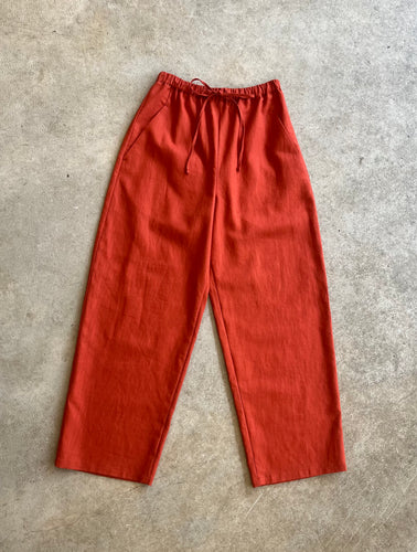 Red linen trousers on a gray concrete floor