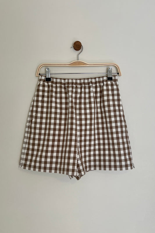Brown and white checkered shorts on a hanger against a plain background