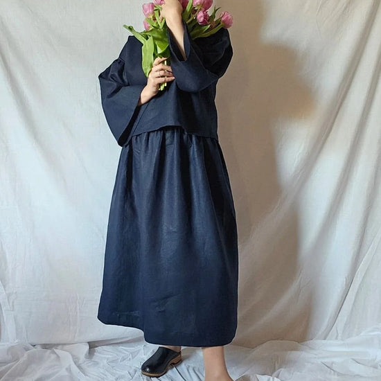 Person wearing a navy blue outfit holding flowers against a plain white background