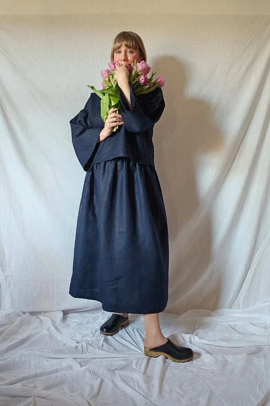 Person wearing a navy blue outfit holding flowers against a plain white background