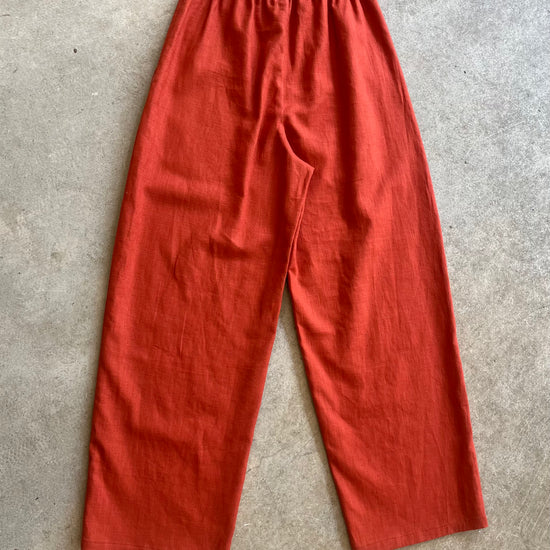 Red linen trousers on a gray concrete surface