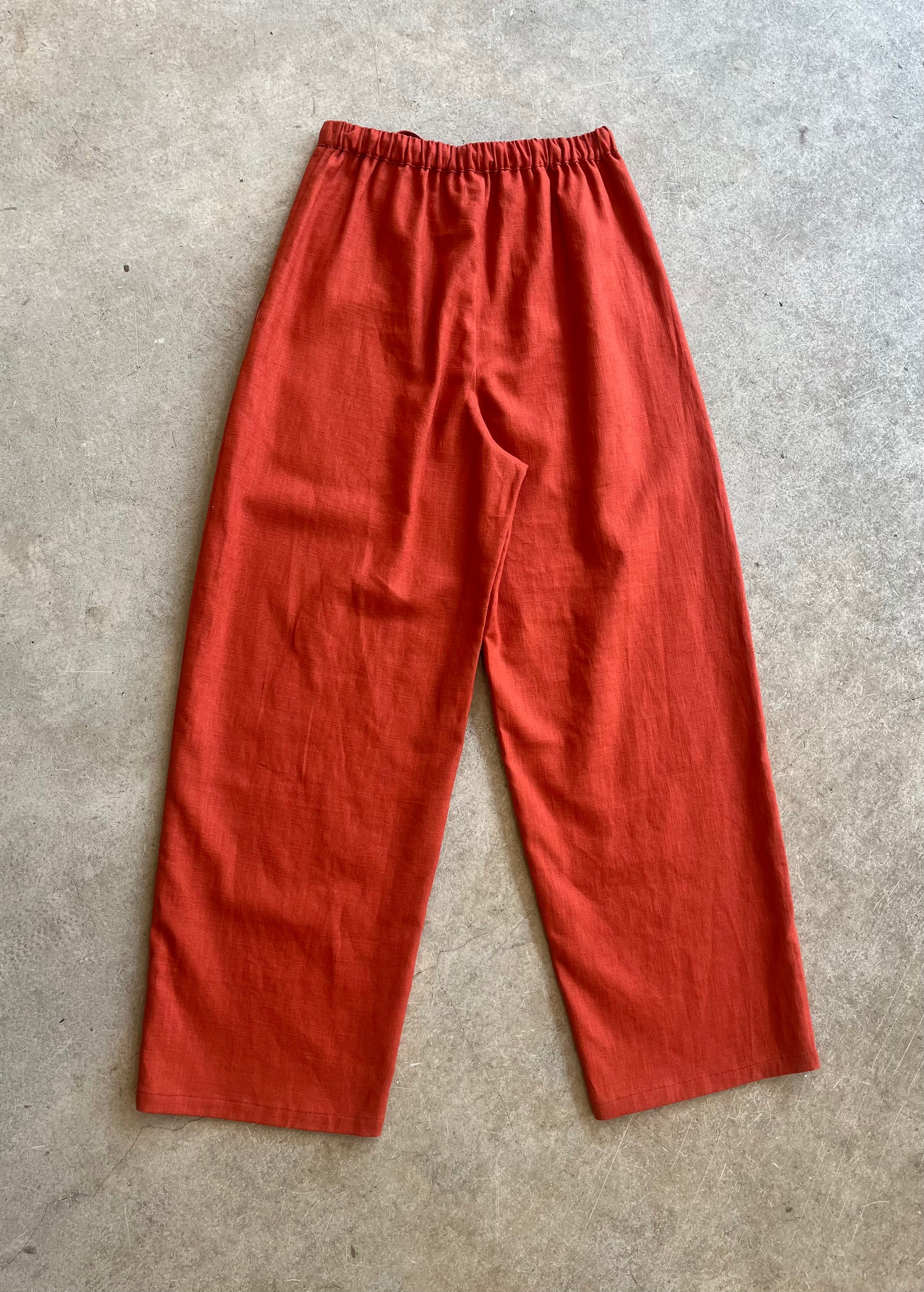 Red linen trousers on a gray concrete surface