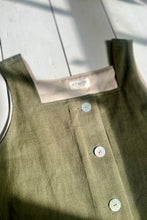 Load image into Gallery viewer, Close-up of a green linen tank with buttons on a wooden surface.

