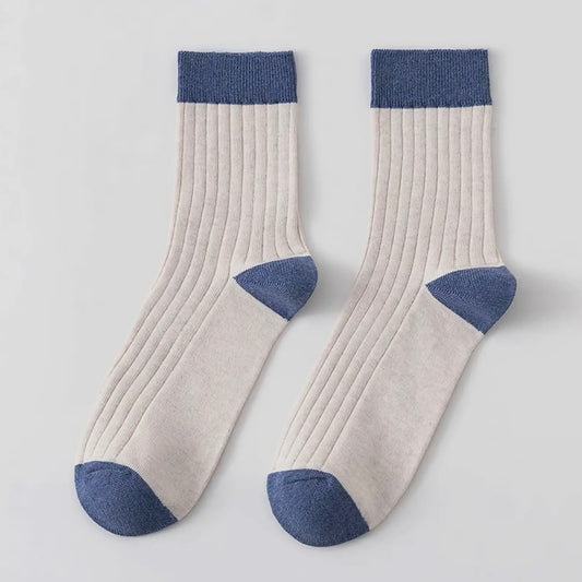 Pair of ecru socks with blue accents on a light grey background